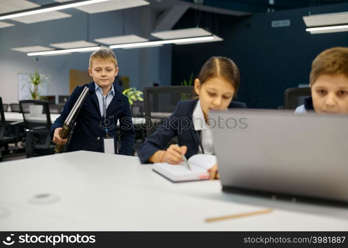 Children working using laptop in modern office. IT education with kids in computer school class. Children working on laptop in modern office