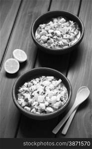 Chilean Ceviche made of Southern Ray&rsquo;s bream fish (lat. Brama Australis, Spanish Reineta), onion, garlic and cilantro marinated in lemon juice served in two rustic bowls. Photographed on dark wood with natural light (Selective Focus, Focus in the middle of the first ceviche) (Monochrome Image)