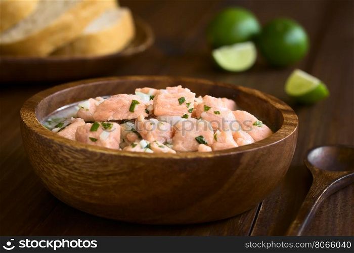 Chilean salmon ceviche prepared with onion, garlic, fresh coriander, salt and lemon juice, photographed with natural light (Selective Focus, Focus on the salmon pieces on the top of the ceviche)