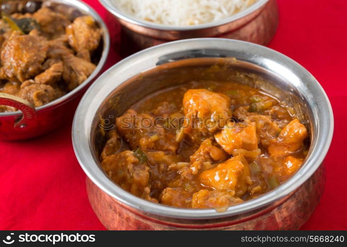 Chili garlic chicken in a serving bowl with rice and chicken malabar behind.