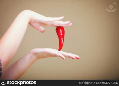 chili pepper in female hand brown background