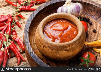 Chili peppers and chili sauce.Hot sauce from chilli peppers and tomatoes. Chili sauce in bowl