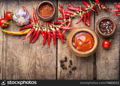 Chili peppers and chili sauce.Hot sauce from chilli peppers and tomatoes on wood background. Spicy chili sauce or ketchup