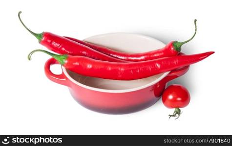Chili peppers on the saucepan and cherry tomatoes near isolated on white background
