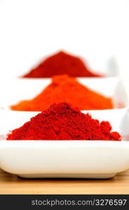 Chili Powder. Cayenne, New Mexico and Arbol chili powder in a white compartmentalized saucer with a small mortar and Pestle