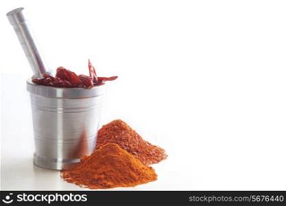 Chili powder with chili peppers in mortar and pestle over white background