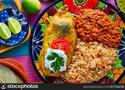 Chili relleno chili pepper poblano filled with cheese in dish with with rice and frijoles beans