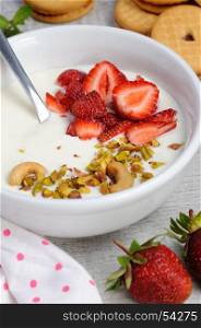 Chilled Buttermilk soup from Greek yogurt with strawberries and pistachios, cashews. Serve with crispy biscuits. Vertical shot.