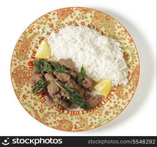 Chilli beef with crispy fried basil leaves, served with white basmati rice and lemon wedges, viewed from above