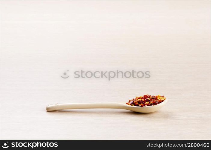 Chilli Flakes in a spoon over a blured wooden background with copy space