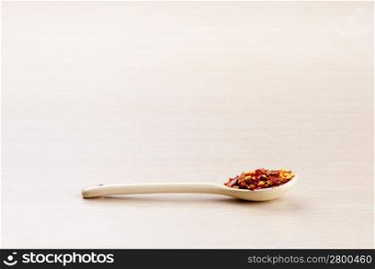Chilli Flakes in a spoon over a blured wooden background with copy space