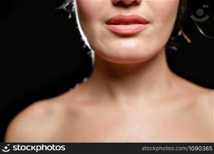 chin and lips, part of the face and bare shoulders of a young woman on a black isolated background