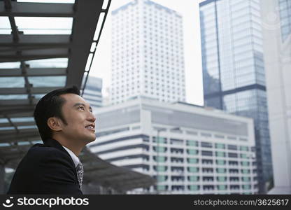 China, Hong Kong, business man looking at cityscape, side view
