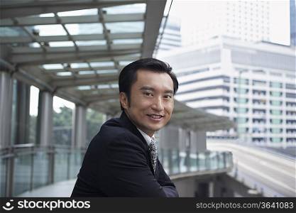 China, Hong Kong, business man standing on footbridge, portrait