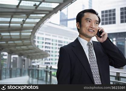 China, Hong Kong, business man using mobile phone, standing on footbridge