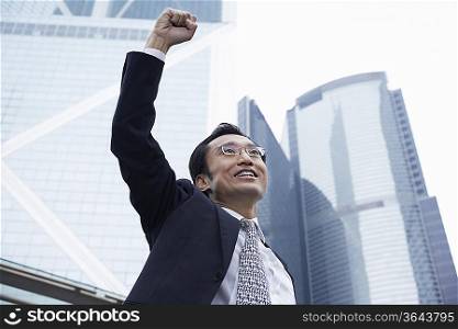 China, Hong Kong, business man with risen fist, low angle view