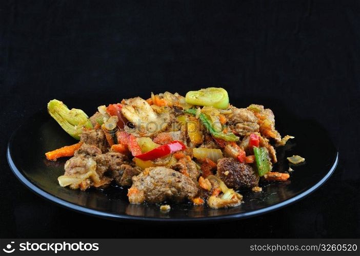 Chines meat with vegetable on black plate