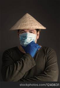 Chinese adult man in traditional Asian conical straw hat stands in virus-protected medical mask on a dark background