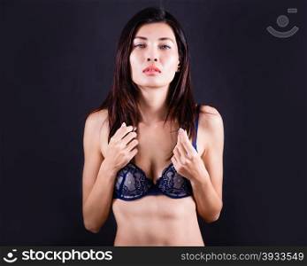 Chinese Asian woman wearing blue bra on dark background