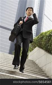 Chinese Businessman Rushing Down Steps On Mobile Phone
