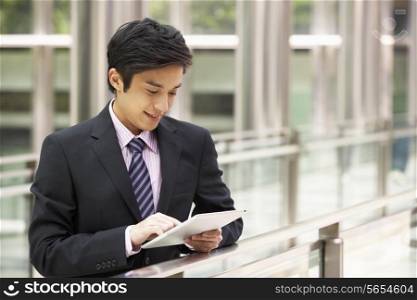 Chinese Businessman Working On Tablet Computer Outside Office