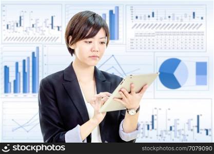 Chinese businesswoman in casual office clothes working on tablet computer with stock market charts background
