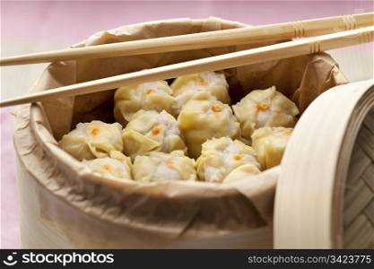 Chinese Dim Sum in a steaming basket with chopsticks