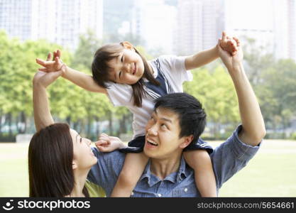 Chinese Family Giving Daughter Ride On Shoulders In Park