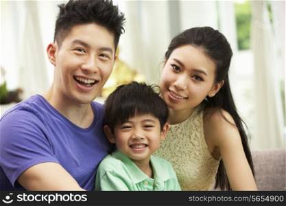 Chinese Family Sitting And Relaxing On Sofa Together At Home