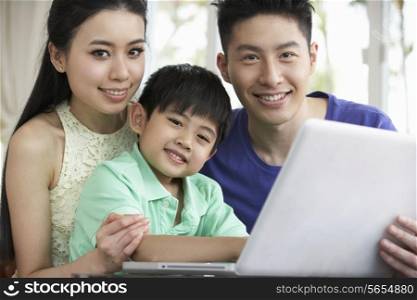 Chinese Family Sitting At Desk Using Laptop At Home