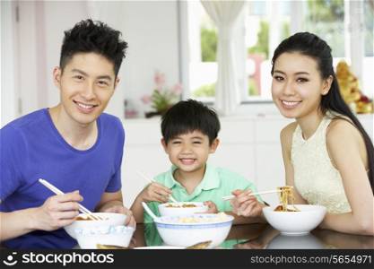 Chinese Family Sitting At Home Eating A Meal