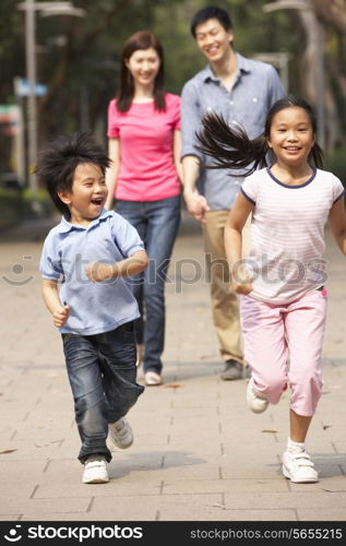 Chinese Family Walking Through Park With Running Children
