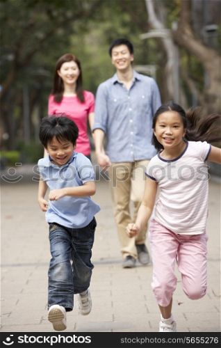 Chinese Family Walking Through Park With Running Children