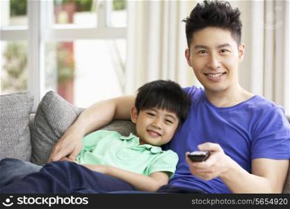 Chinese Father And Son Sitting And Watching TV On Sofa Together