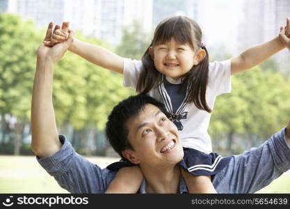 Chinese Father Giving Daughter Ride On Shoulders In Park