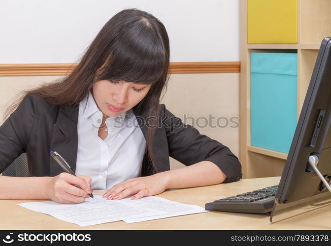 Chinese female writing at office desk