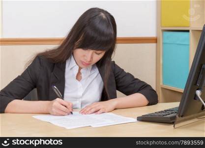Chinese female writing at office desk