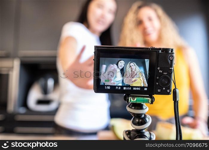 chinese girl and white girl shooting a video in the kitchen for blog