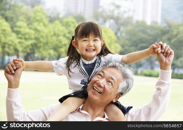 Chinese Grandfather Giving Granddaughter Ride On Shoulders In Park