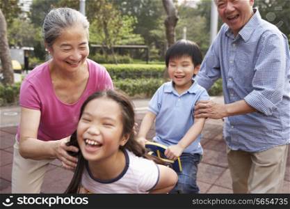 Chinese Grandparents Playing With Grandchildren In Playground