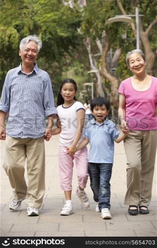 Chinese Grandparents Walking Through Park With Grandchildren