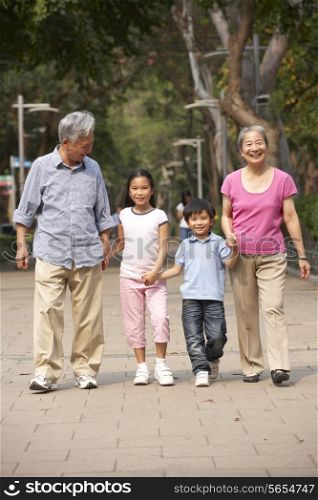 Chinese Grandparents Walking Through Park With Grandchildren