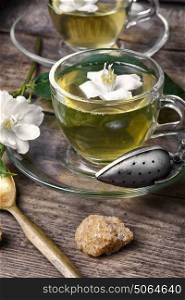 Chinese green tea with Jasmine. glass of herbal tea with the aroma of Jasmine flower on wooden background