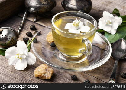 Chinese green tea with Jasmine. glass of herbal tea with the aroma of Jasmine flower on wooden background