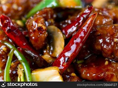 Chinese hot red Chile peppers with chicken and vegetables. Filled frame format with selective focus on front pepper.
