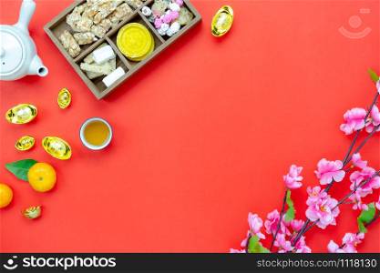 Chinese language mean rich or wealthy and happy.Table top view Lunar New Year & Chinese New Year vacation concept background.Flat lay orange in wood basket & white flower on modern rustic red backdrop