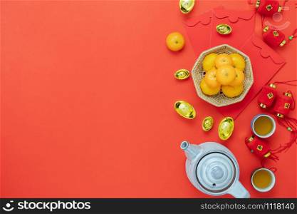 Chinese language mean rich or wealthy and happy.Table top view Lunar New Year & Chinese New Year vacation concept background.Flat lay orange & cup of tea with lantern and gold money on red backdrop.