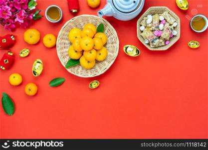 Chinese language mean rich or wealthy and happy.Table top view Lunar New Year & Chinese New Year concept background.Flat lay orange in wood basket & sweet dessert with blossom on rustic red backdrop.