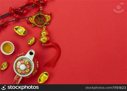 Chinese language mean rich or wealthy and happy.Top view aerial image decoration Chinese new year & lunar new year holiday background concept.Flat lay cup of tea & fortune with blossom on red paper.
