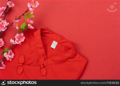 Chinese language mean rich or wealthy and happy.Accessories on Lunar New Year & Chinese New Year vacation concept background.Red T-shirt with pink cherry flower on modern red paper.copy space design.